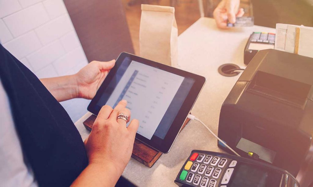 Primo piano sul tablet utilizzato dalla cassiera di una piccola impresa per emettere uno scontrino elettronico
