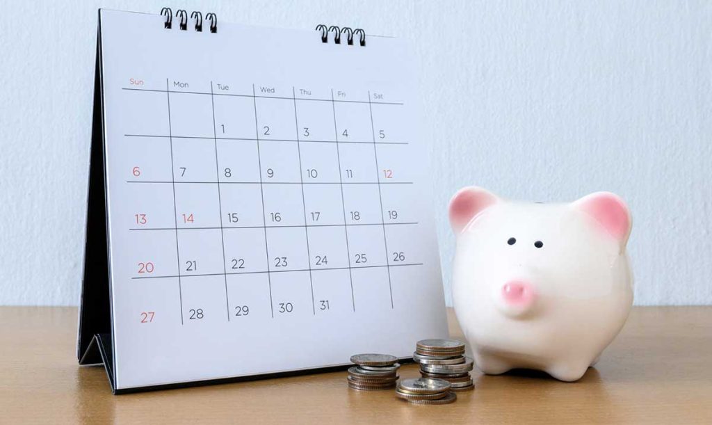 Calendario da scrivania con salvadanaio e monete ad indicare la scadenza del pagamento