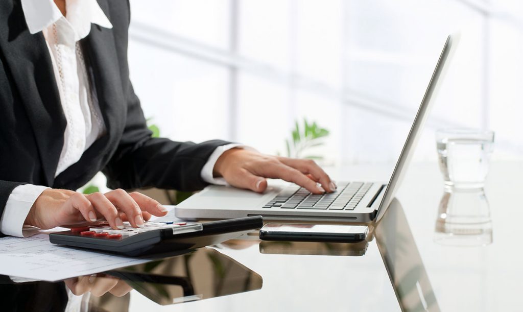 Mani femminili che lavorano su calcolatrice e computer portatile per fare un preventivo efficace