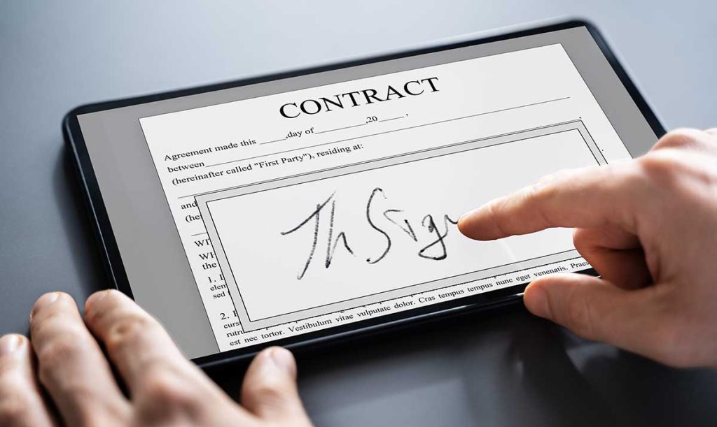 Dettaglio della mano su un tablet mentre appone una firma con il sistema touch