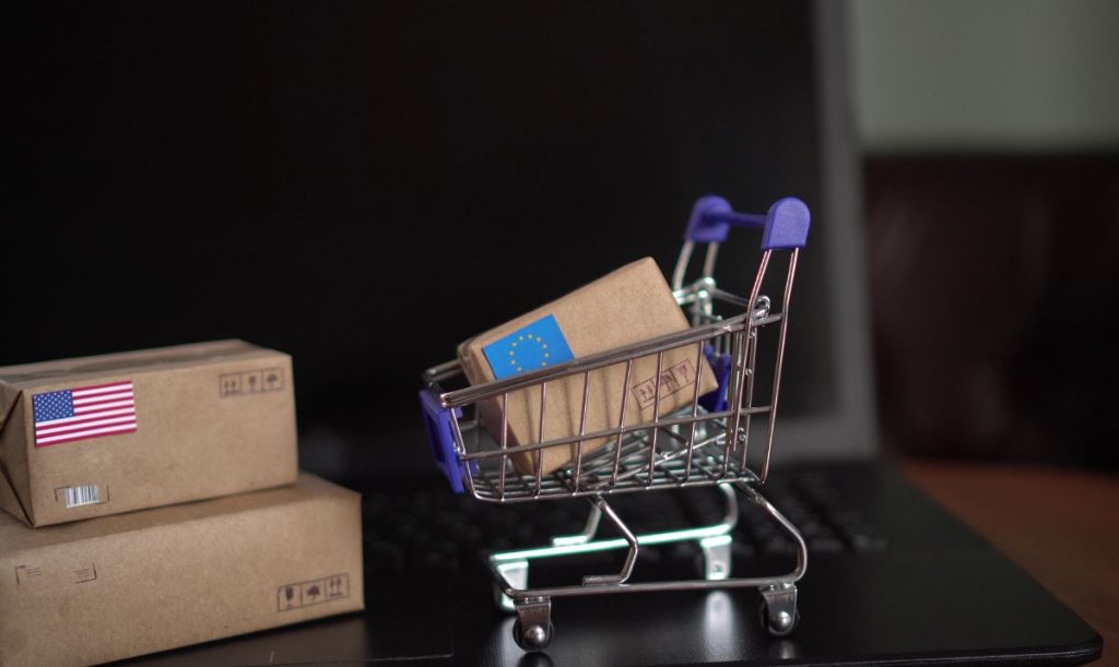 Pacchi e miniatura di un carrello della spesa poggiati su un laptop