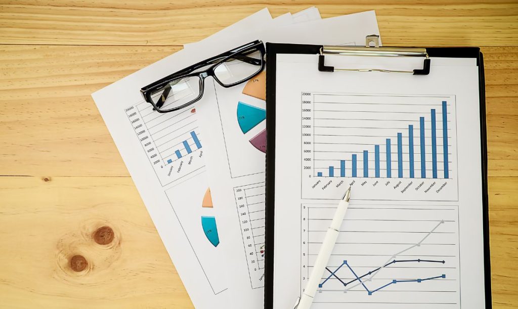 Occhiali da vista e fogli di un bilancio di esercizio poggiati su piano in legno