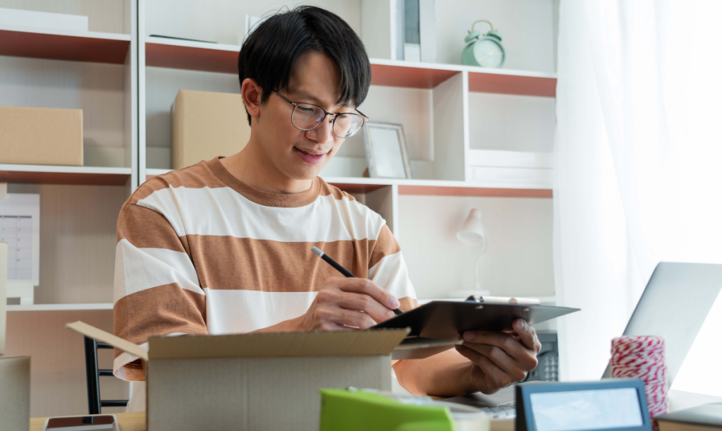 Venditore che legge l'elenco dei prodotti mentre prepara la scatola per la spedizione