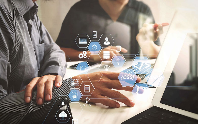 perche-alias-digital Concetto di riunione del team: sviluppatori riuniti ad un tavolo per analizzare lo sviluppo di un software parte dell'ecosistema Alias Digital