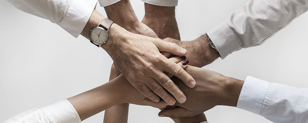 team_alias-digital-1-a Concetto di lavoro di squadra in Alias Digital, persone del team che uniscono le mani insieme.