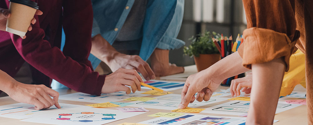 team_alias-digital-2-a Primo piano del tavolo di lavoro del team di Alias Digital mentre sviluppa un progetto