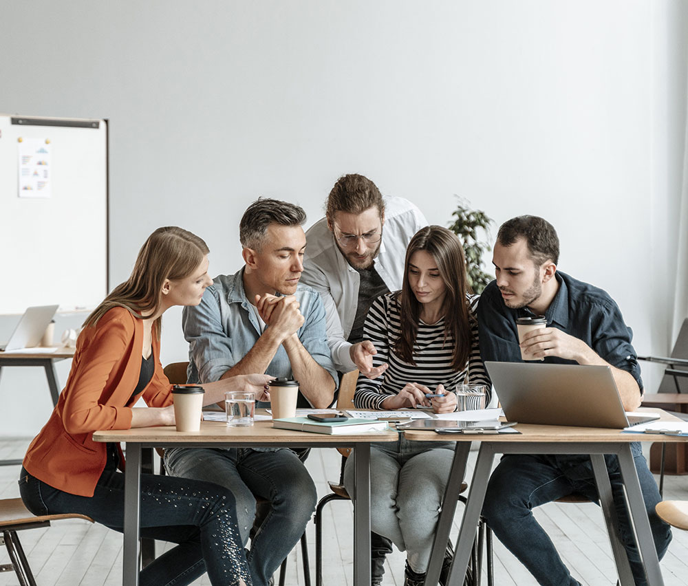 team_alias-digital Il team di Alias Digital riunito alla scrivania per collaborare su un progetto