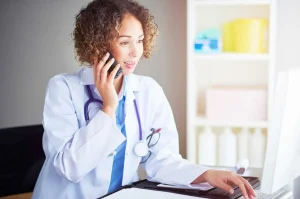 Una dottoressa sorridente che lavora al computer in clinica