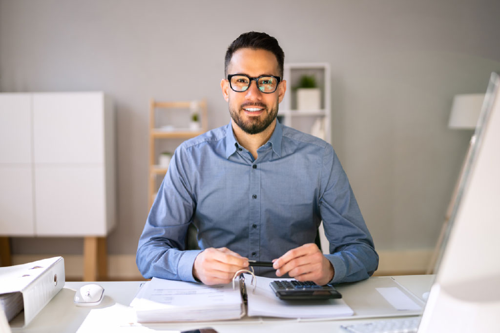 Commercialista alla scrivania mentre consulta visure e bilanci online con Visurapronta